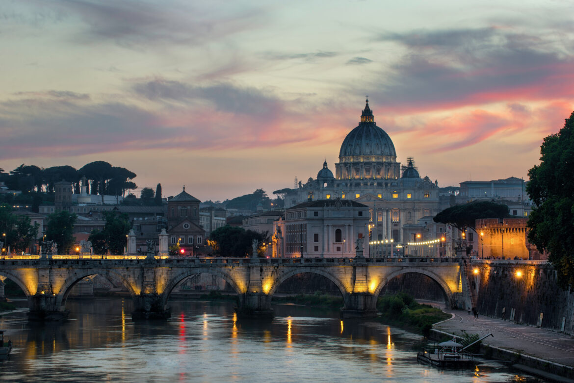Basilica di San Pietro al tramonto con il Tevere e il ponte illuminato a Roma