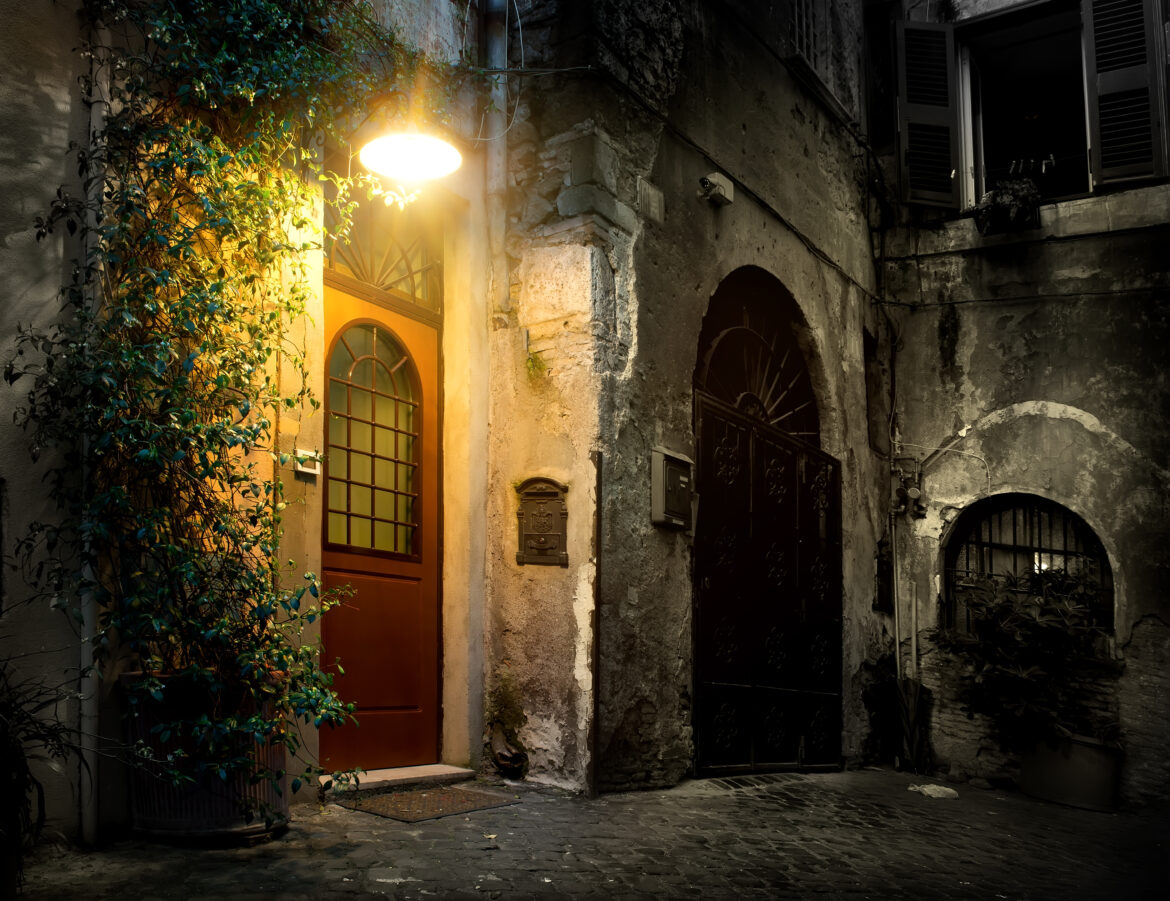 vicolo del centro storico di Roma con porta illuminata e atmosfera serale
