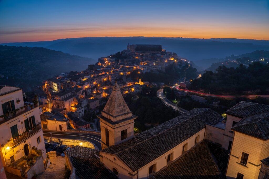 Veduta panoramica di Ragusa Ibla illuminata all’ora blu, con il centro storico barocco immerso tra le colline del Val di Noto.