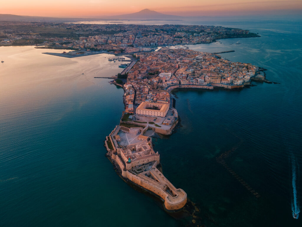 Vista aerea di Ortigia al tramonto con il centro storico di Siracusa affacciato sul Mar Ionio.