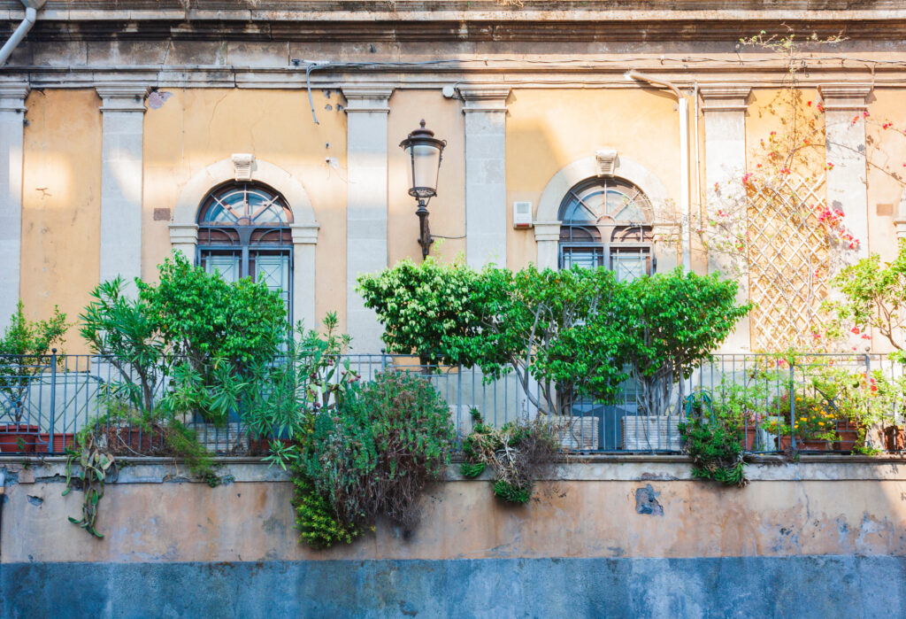 Facciata storica con terrazza e piante nel centro di Catania