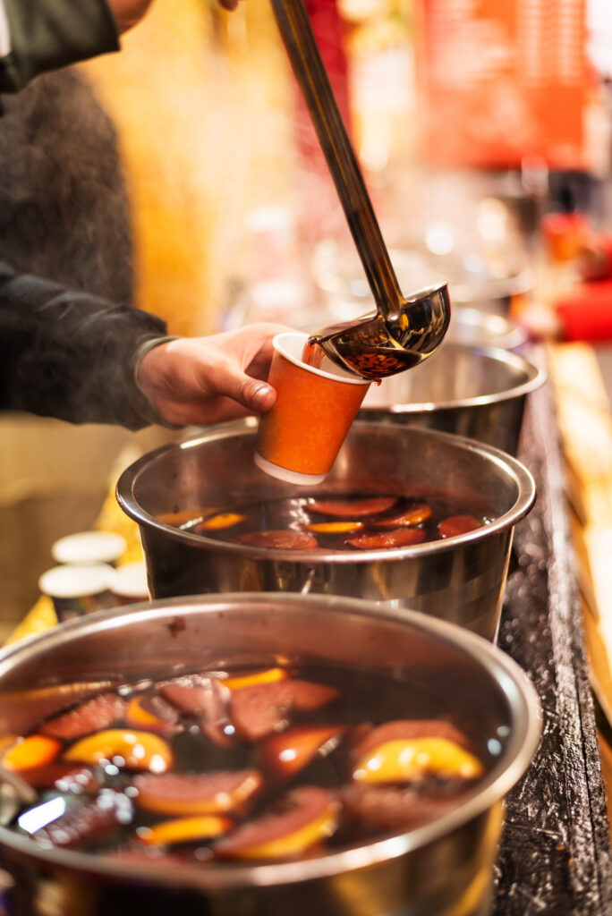 Vin brulé caldo versato con un mestolo in un bicchiere durante un mercatino natalizio
