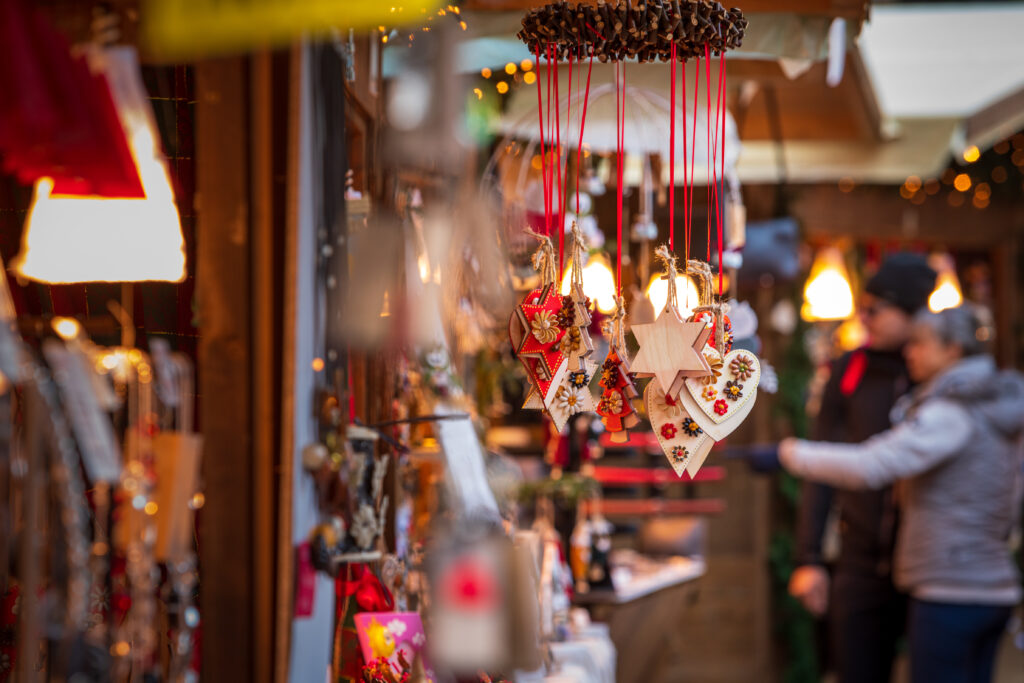 Decorazioni natalizie in legno a forma di stella e cuore appese a una bancarella di un mercatino di Natale