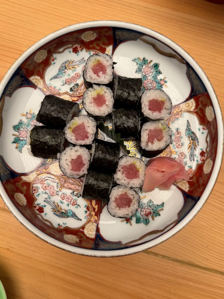 Hosomaki al tonno con riso e alga nori, serviti su un piatto giapponese decorato con zenzero marinato.