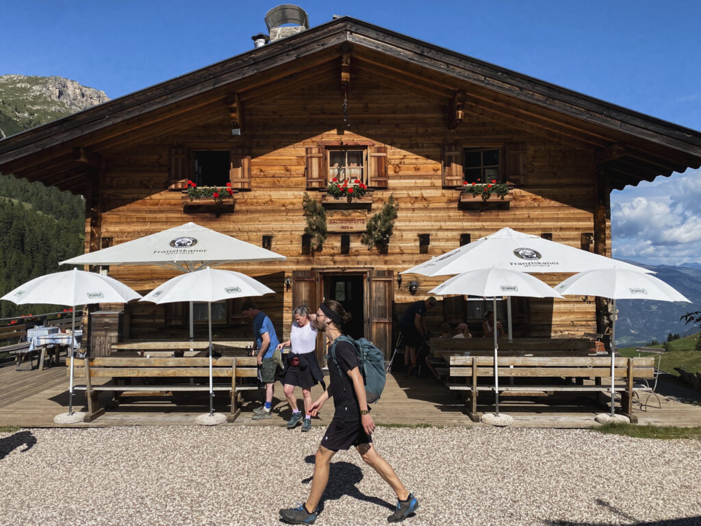 Rifugio alpino in legno con terrazza e ombrelloni durante una giornata estiva