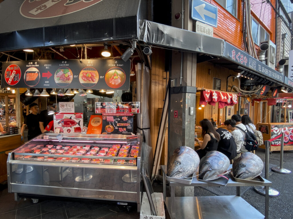 Scena urbana a Osaka con una persona che consulta il telefono lungo una strada commerciale