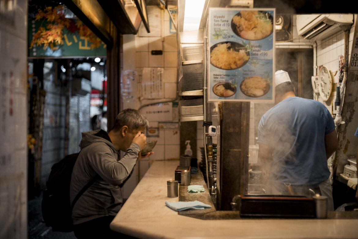 Cliente che mangia noodles al bancone di un ristorante tradizionale giapponese