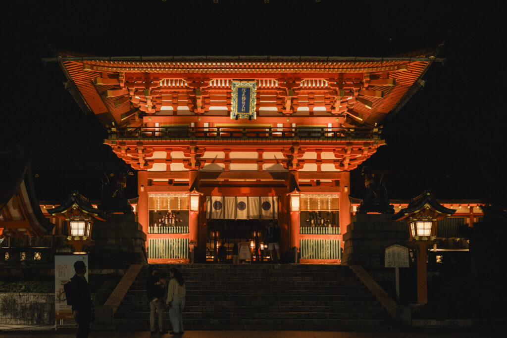 Portale tradizionale rosso del santuario Fushimi Inari a Kyoto, illuminato durante la notte.