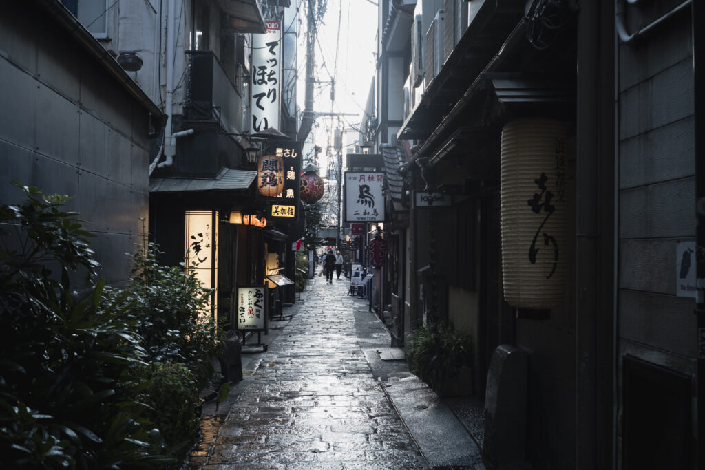 Stretto vicolo di Osaka illuminato da lanterne e insegne di ristoranti giapponesi