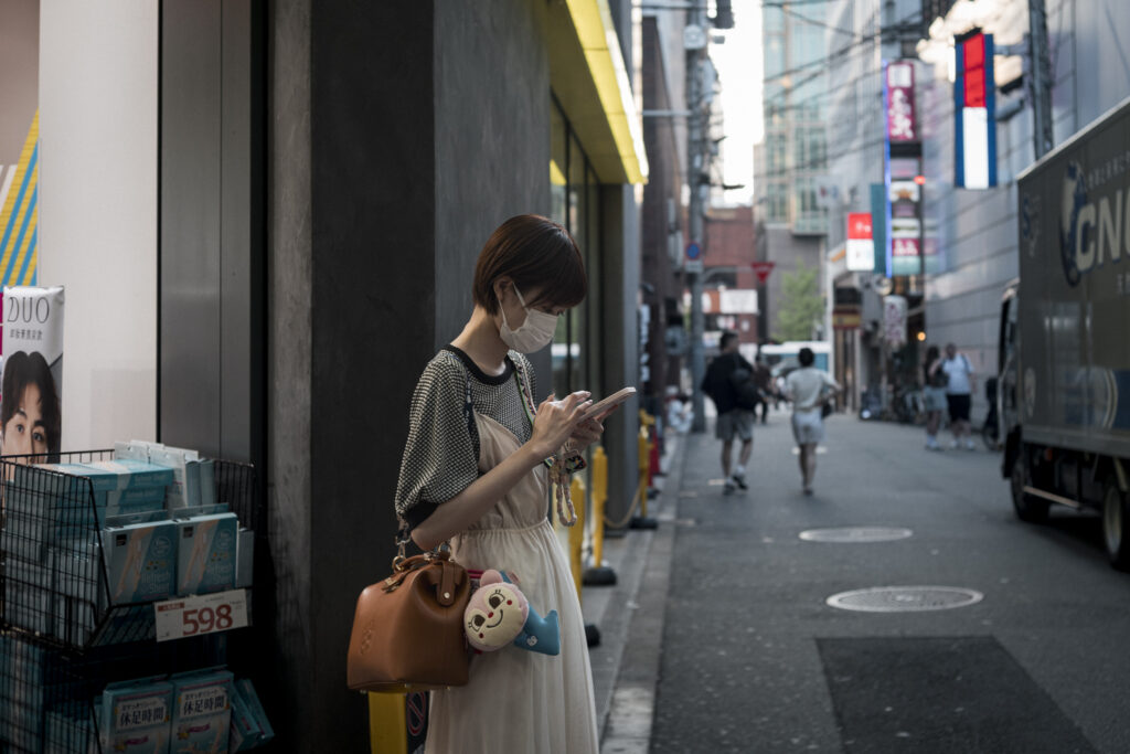 Scena urbana a Osaka con una persona che consulta il telefono lungo una strada commerciale